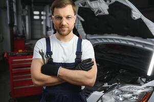 porträtt av en leende fixering en bil motor i hans garage foto