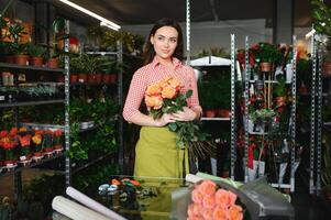 söt flicka blomsterhandlare samlar en bukett av ro i en blomma affär. en skön blomsterhandlare skapar en sammansättning av blommor. flicka nedskärningar blommor och tar bort unken löv foto