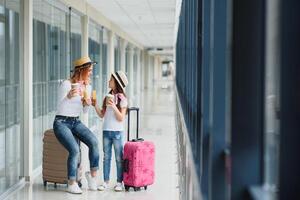 familj på flygplats innan flyg. mor och unge väntar till styrelse på avresa Port av modern internationell terminal. reser och flygande med barn. mamma med bebis på ombordstigning flygplan. foto