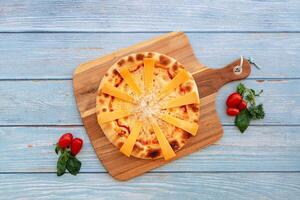 trippel- ost pizza med tomat körsbär eras i maträtt isolerat på trä- tabell topp se snabbmat foto