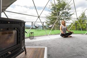 kvinna håller på med yoga glamping hus . friska livsstil begrepp. helgen flykt på glamping. mental läkning foto