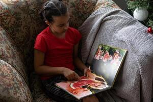 liten flicka ser fotobok på Hem. stänga upp skott. familj, barndom och fritid begrepp foto