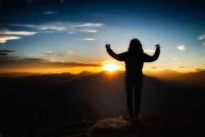 flicka i yogameditation på toppen av ett berg i solnedgången foto