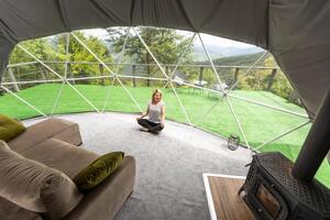 transparent bubbla tält på glamping, frodig skog runt om och interiör. kvinna vilar i glamping foto