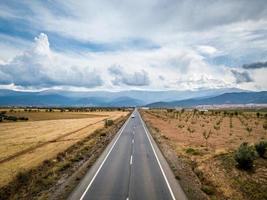 Flygfoto över rak tjärad väg genom guadix, granada. i bakgrunden sierra nevada foto