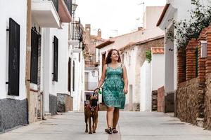 ung kvinna går nerför gatan med boxerhund foto