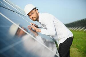 positiv skäggig manlig investerare stående mot solceller paneler producerar alternativ energi. foto