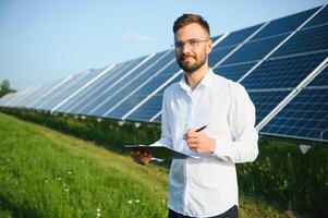 positiv skäggig manlig investerare stående mot solceller paneler producerar alternativ energi. foto