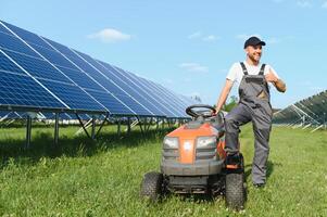 en man klipper de gräs nära de sol- paneler. grön energi foto