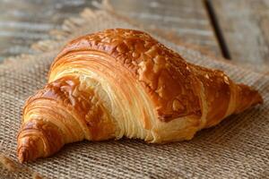 ai genererad gyllene croissant på rustik tabell, en fjällig och smörig franska bakverk perfekt för frukost foto