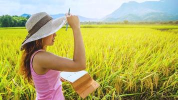 asiatiska kvinnor koppla av i semestern. skriv en anteckning i anteckningsboken. skriva en studie av naturlig trädgårdsträdgård.