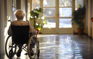 ai genererad äldre kvinna sitter i rullstol i hall av amning Hem. foto