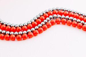 en halsband av röd och grå pärlor på en vit estetisk bakgrund. foto