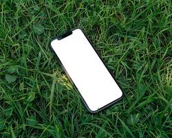 ai genererad modern smartphone attrapp scen. smartphone attrapp mall med tom vit skärm på grön gräs. foto