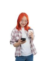 en kvinna med röd hår och glasögon är innehav en cell telefon och en kopp. hon är leende och hon är njuter henne tid. isolerat på vit bakgrund foto