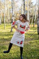 vacker kvinna i ukrainska nationella traditionella kostymkläder dansar i skogen foto