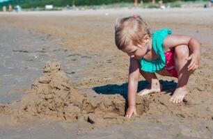 ung Lycklig barn flicka av europeisk utseende ålder av 4 har roligt på de strand och byggnad sand slott, tropiska sommar yrken, helgdagar.a barn åtnjuter de sea.copy Plats foto