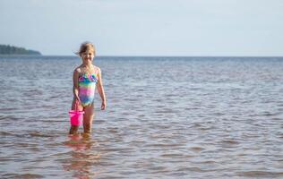 ung Lycklig barn flicka av europeisk utseende ålder av 6 har roligt i vatten på de strand ,tropisk sommar yrken, helgdagar.a barn åtnjuter de hav.familj högtider koncept.kopia Plats. foto