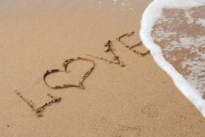 kärlek text på de sandig strand och hav vatten. foto