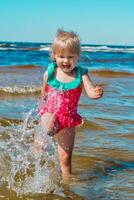 ung Lycklig barn flicka av europeisk utseende ålder av 4 har roligt i vatten på de strand och stänk, tropiskt sommar yrken, helgdagar.a barn åtnjuter de hav.vertikal Foto. foto