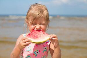 glad barn äter saftig vattenmelon.barn känslor tjej äter vattenmelon på de bakgrund av de havet, den strandfamilj sommar högtider på de hav koncept.kopia Plats. foto