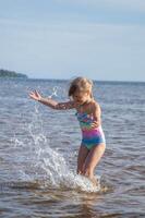 ung Lycklig barn flicka av europeisk utseende ålder av 6 har roligt i vatten på de strand och stänk, tropiskt sommar yrken, helgdagar.a barn åtnjuter de hav.vertikal Foto. foto