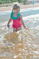 ung Lycklig barn flicka av europeisk utseende ålder av 4 har roligt i vatten på de strand ,tropisk sommar yrken, helgdagar.a barn åtnjuter de hav.vertikal photo.copy Plats foto