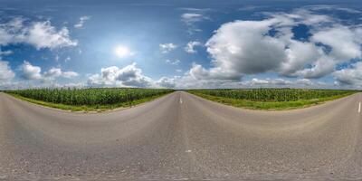 sfärisk 360 hdri panorama på gammal asfalt väg bland majs fält med moln och Sol på blå himmel i likriktad sömlös utsprång, som skydome ersättning i Drönare panoramabilder, spel utveckling foto