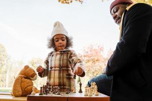svart farfar och barnbarn spelar schack i höst park