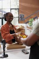 afrikansk amerikan kvinnor presenter nyligen plockade citroner på de kassör skrivbord. bild visa upp en kvinna kund erbjudande frukt till en svart Säljare till väga. foto
