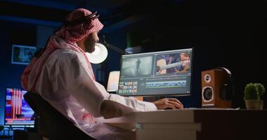 arabicum färgist frilansare bär hörlurar medan redigering projekt, söm videoklipp tillsammans, arbetssätt med bilder och ljud. själv sysselsatt man bearbetning film på pc arbetsstation foto