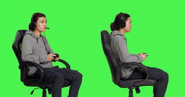 gamer har roligt med rPG utmaning över grönskärm bakgrund, spelar Videospel med kontroller. ung asiatisk kille njuter uppkopplad spel, video spel spelare med samordning skicklighet. foto