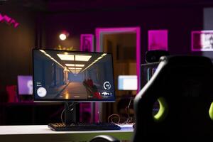 professionell gaming tömma rum studio med neon lampor och rgb belyst kraftfull dator, först person skytten spel vänster öppen på skärm. fps TV-spel på pc visa i lägenhet sent på natt foto