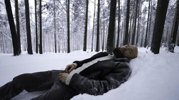 man lögner i snö i vinter- skog. media. trött man lögner i snödriva i vinter- skog. depressiv eleganta man lögner i snö i vinter- skog foto