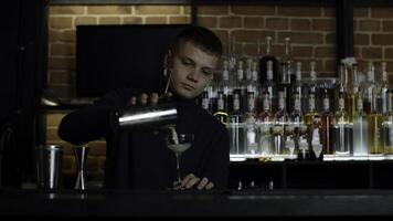 de bartender framställning perfekt cocktail, stående Bakom de bar disken. media. många flaskor av alkohol på de bakgrund. foto