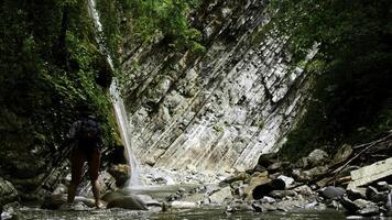 skön vattenfall i grön skog. kreativ. kvinna korsning tropisk flod i berg djungel. foto