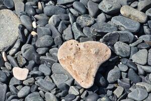 Fantastisk hjärta formad naturlig sten på en säng av stenar foto