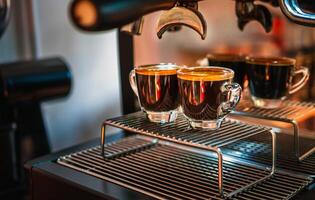 stänga upp av espresso skott med kaffe crema och professionell kaffe maskin medan framställning två espressos skott glas i en kaffe affär. foto