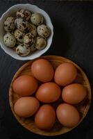 färsk kyckling och vaktel ägg i vit och trä- tallrik på sten selektiv fokus. foto