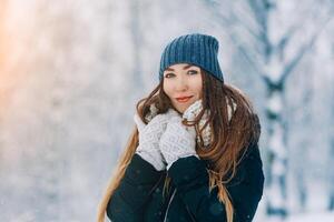 vinter- ung kvinna porträtt. skönhet glad modell flicka skrattande och har roligt i vinter- parkera. skön ung kvinna utomhus. njuter natur, vintertid foto