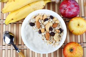 naturlig yoghurt med hemlagad granola och nötter i keramisk skål på en tabell topp se foto