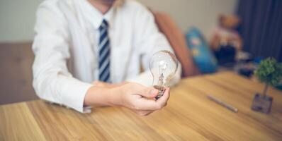 företag professionell innehav en ljus Glödlampa i en kreativ brainstorming session, symboliserar idéer och innovation foto
