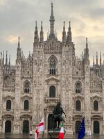 milano, Italien - 12 november 2023. staty av kung segrare emmanuel ii i främre av de duomo katedral mot en molnig himmel. milano, Italien foto