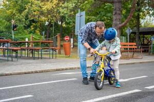 ung far lär barn dotter till rida offentlig cykel på ett av trafik lekplats av Prag, tjeck republik. hög kvalitet Foto