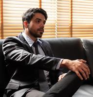 ung mellanöstern stilig affärsman klädd i kostym och slips sitter på soffan på kontoret. affärsidé foto