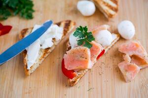 friterad rostat bröd med lax, grädde ost, sallad, på en trä- tabell foto