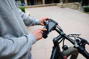 närbild cyklist checkar mobil app på smartphone attrapp digital Rör skärm, miljö upp en rutt på internet uppkopplad Karta foto