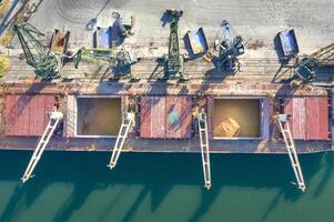 topp se från en Drönare av en stor fartyg läser in spannmål för exportera. vatten transport foto