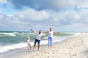 en liten flicka och henne föräldrar promenad på de strand på de baltic hav i litauen foto