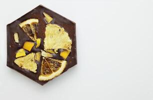 handgjort mörk choklad bar med en torkades frukt garnering - skivor av orange, mango, ananas. hemlagad choklad bark i form av vaxkaka. topp se. isolerat på vit bakgrund. kopia Plats foto